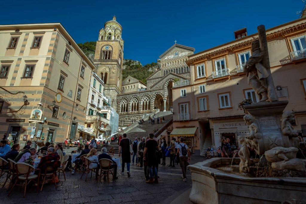 Amalfi Cathedral and Piazza del Duomo with historic buildings, fountain, and visitors in the town of Amalfi on Italy’s Amalfi Coast.