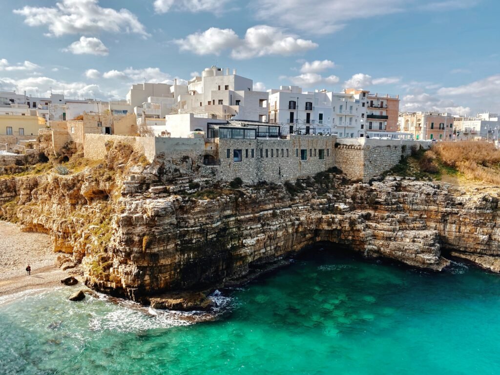 Polignano a Mare from above showing white buildings on the limestone cliffs above brilliant turquoise water