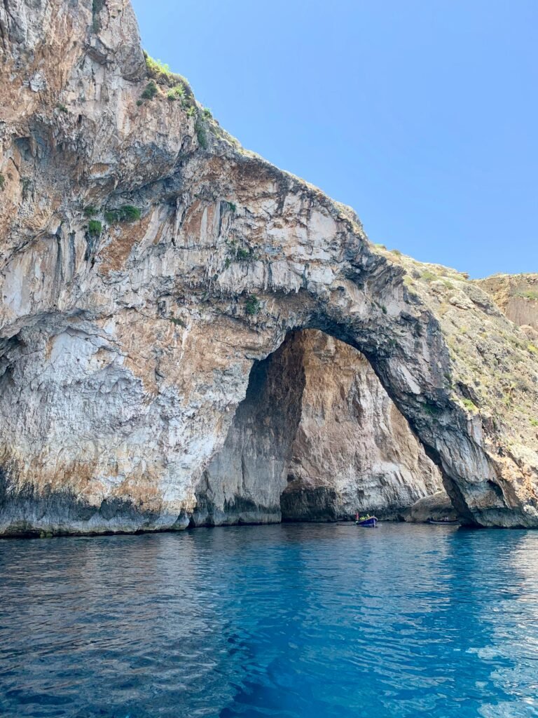 Rocky sea cave entrance near Capri with crystal clear blue water and dramatic limestone cliffs in southern Italy.