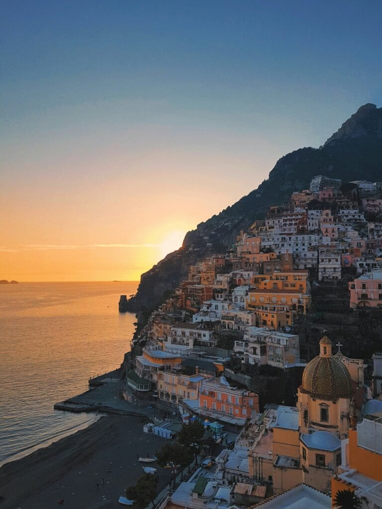 Sunset view over Positano with colorful cliffside buildings, beach, and sea on Italy’s Amalfi Coast.