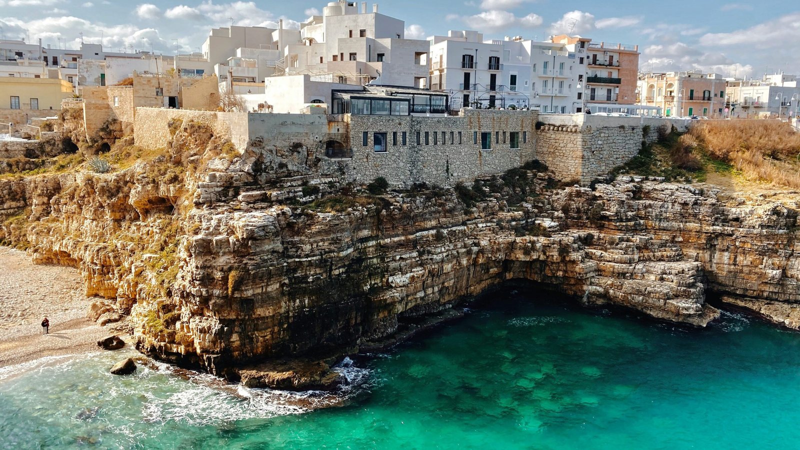 Polignano a Mare from above showing white buildings on the limestone cliffs above brilliant turquoise water