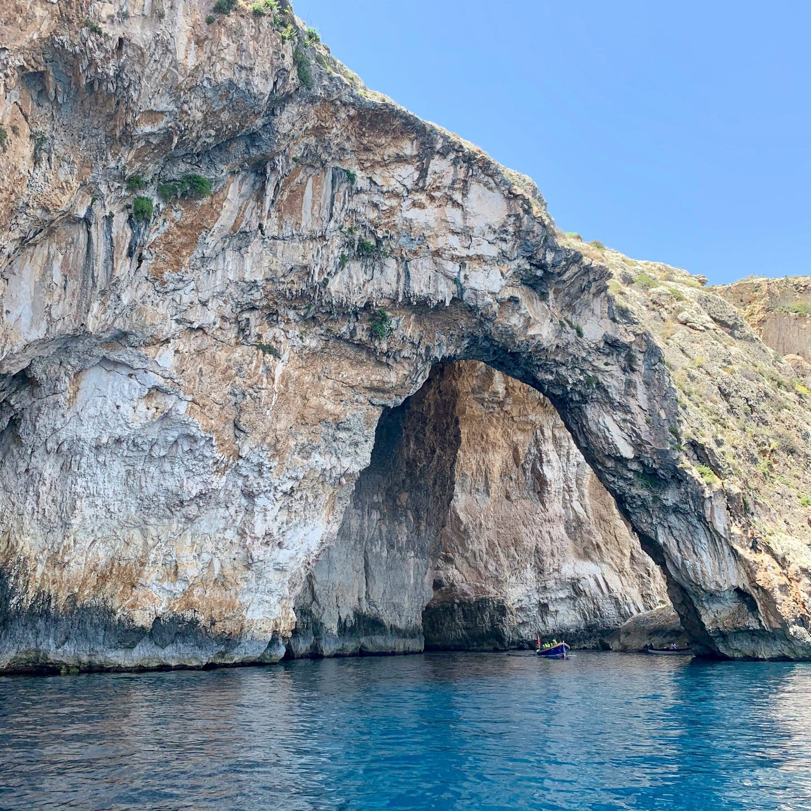Rocky sea cave entrance near Capri with crystal clear blue water and dramatic limestone cliffs in southern Italy.
