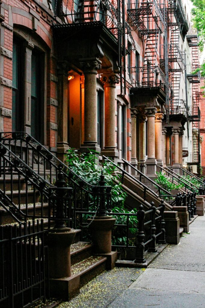 West Village brownstone stoops and fire escapes along a quiet New York City street