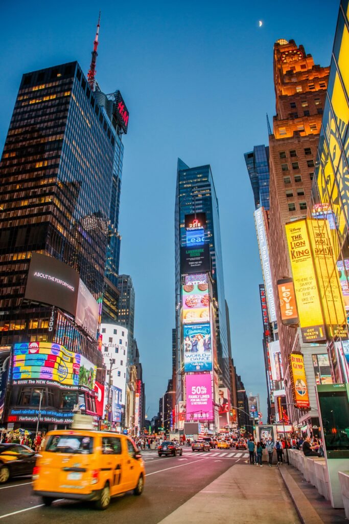 Times Square at blue hour with Broadway billboards, traffic, and a yellow taxi in New York City