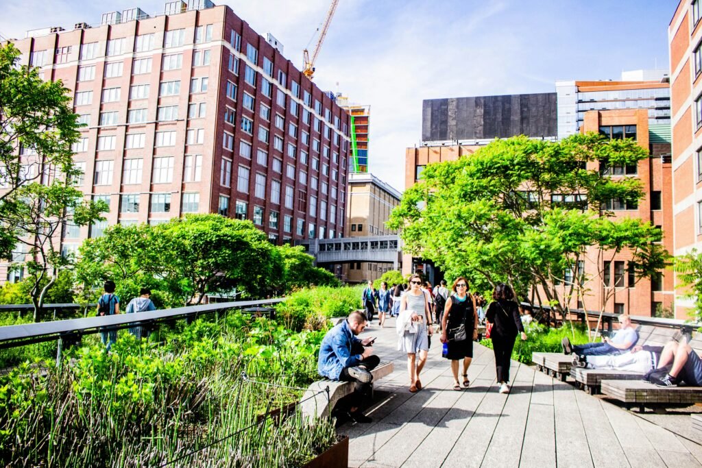 People walking along the High Line elevated park with greenery and Chelsea buildings in New York