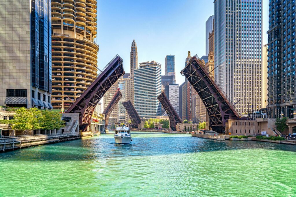 Boat passing under raised bridges on the Chicago River between downtown skyscrapers