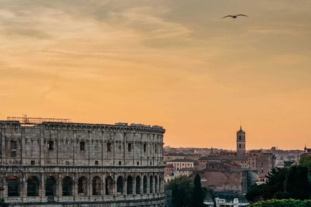 The Colosseum and Rome skyline at sunset with golden sky above the historic center