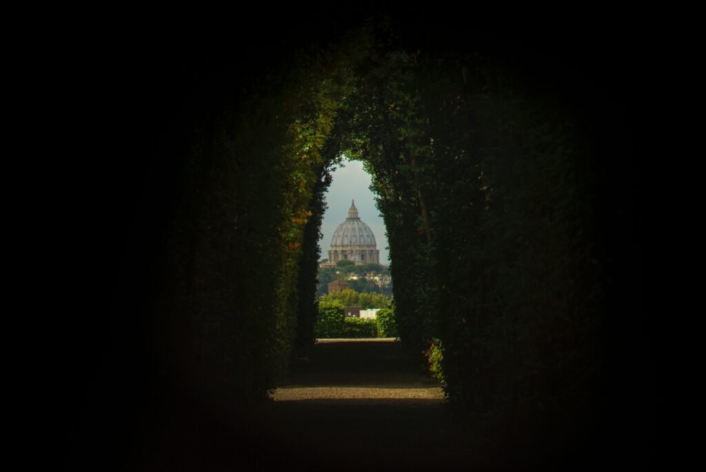 St Peters Basilica dome framed through the dark hedge tunnel of the Aventine Keyhole in Rome