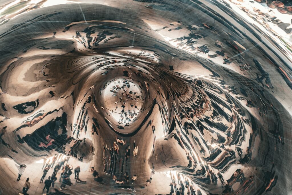 Visitors walking under the mirrored underside of Cloud Gate in Millennium Park