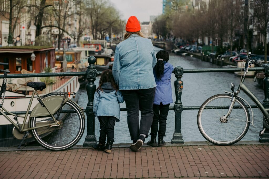 Parent and two children looking over an Amsterdam canal from a bridge