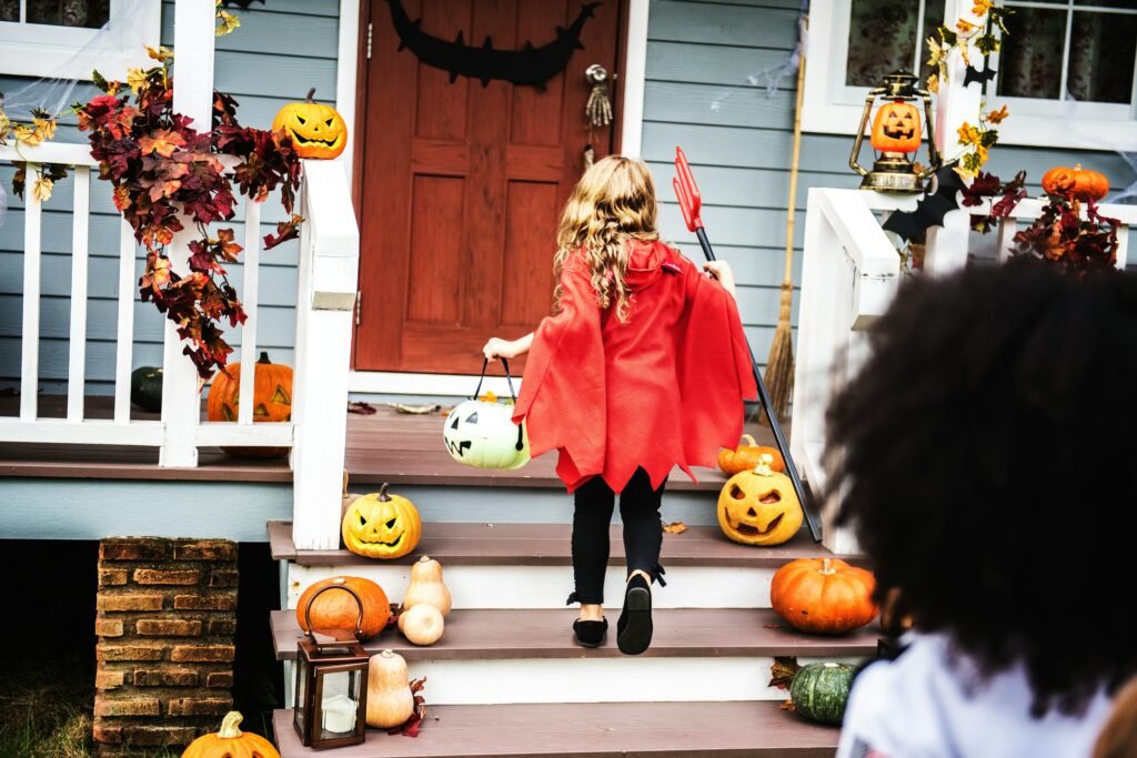 Child in a red Halloween costume trick-or-treating at a decorated house