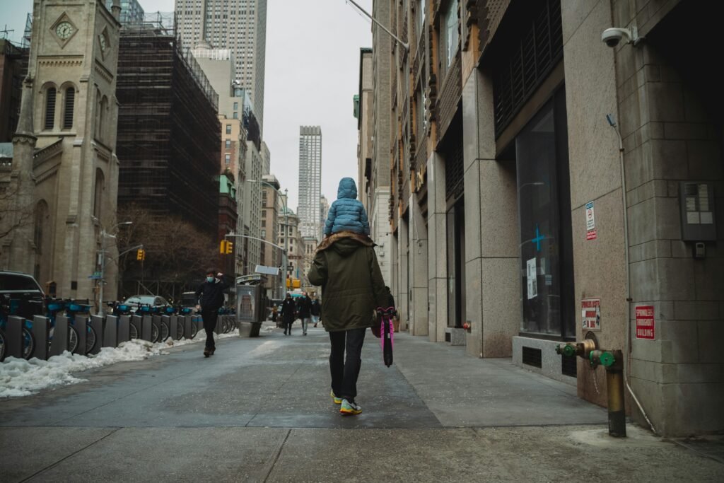 Adult carrying a child on a Midtown Manhattan sidewalk in New York City