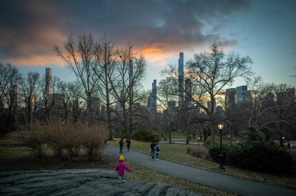 Child walking in Central Park with the Manhattan skyline in the background