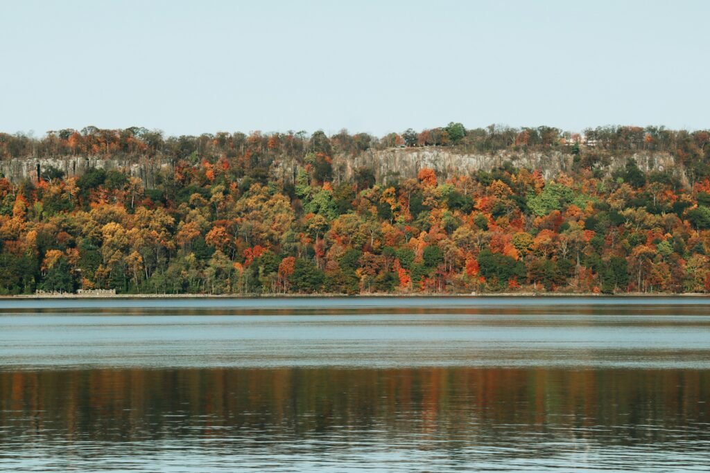 Hudson River cliffs with orange and yellow fall foliage reflected in the water