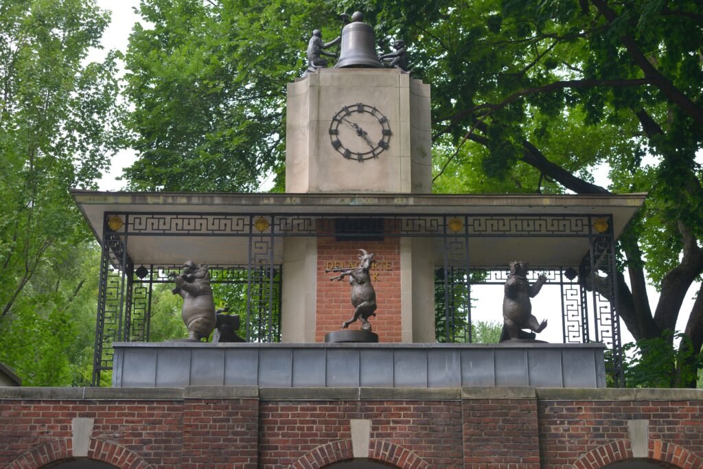 Delacorte Clock outside Central Park Zoo with bronze animal figures under green trees