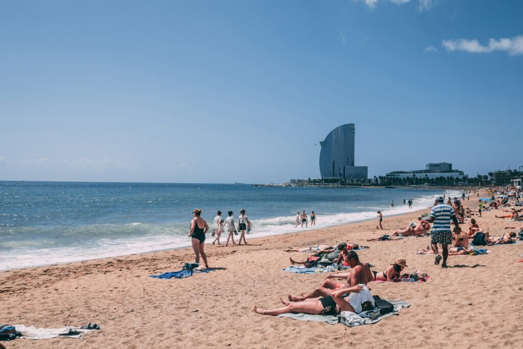 Families relaxing on Barceloneta Beach with the W Barcelona hotel in the background