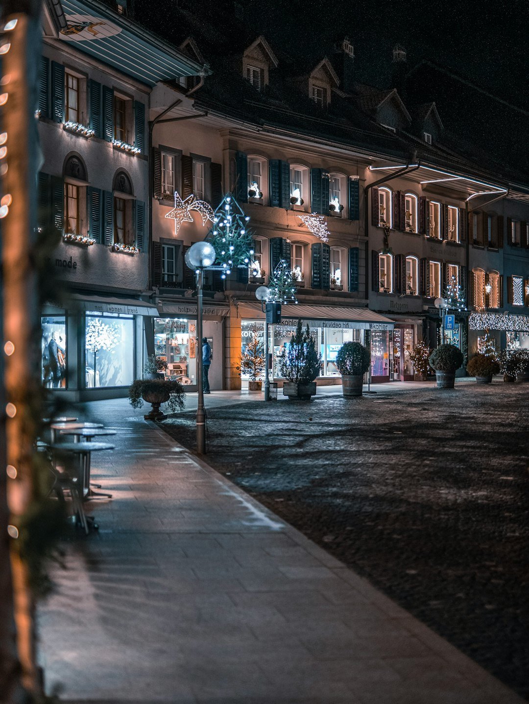 A quiet Bavarian-style village street at night in Leavenworth, Washington, with storefronts lit up and small lighted Christmas trees along the sidewalk