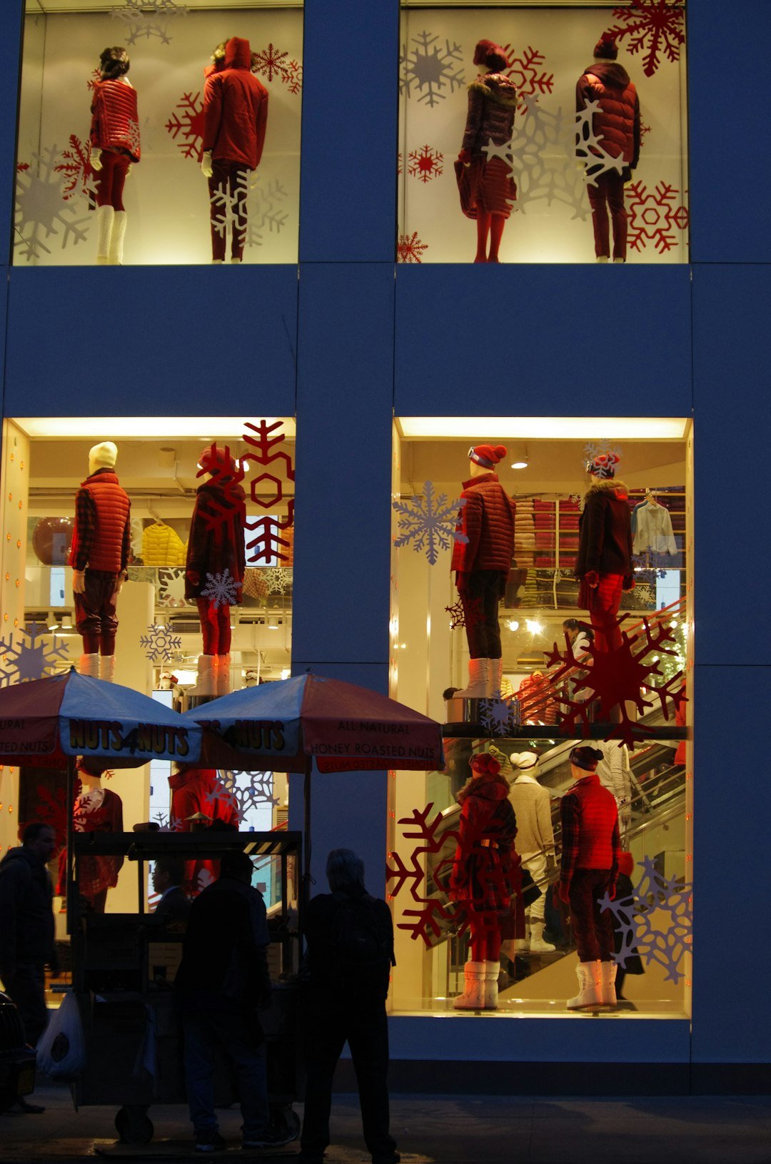 A decorated holiday window display with snowflake motifs at a New York City storefront at night