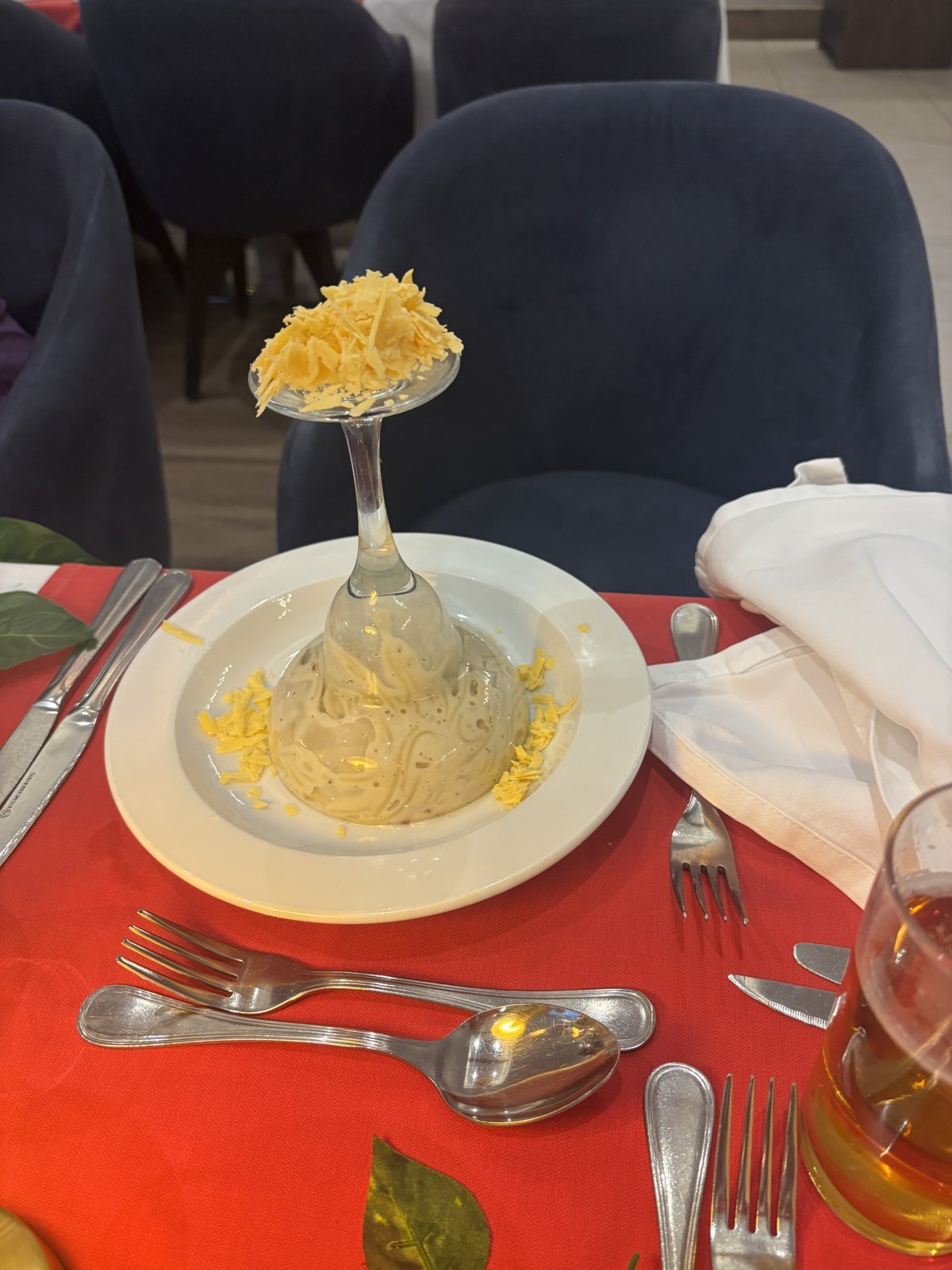 Creamy pasta topped with grated cheese on a white plate, served on a red table runner