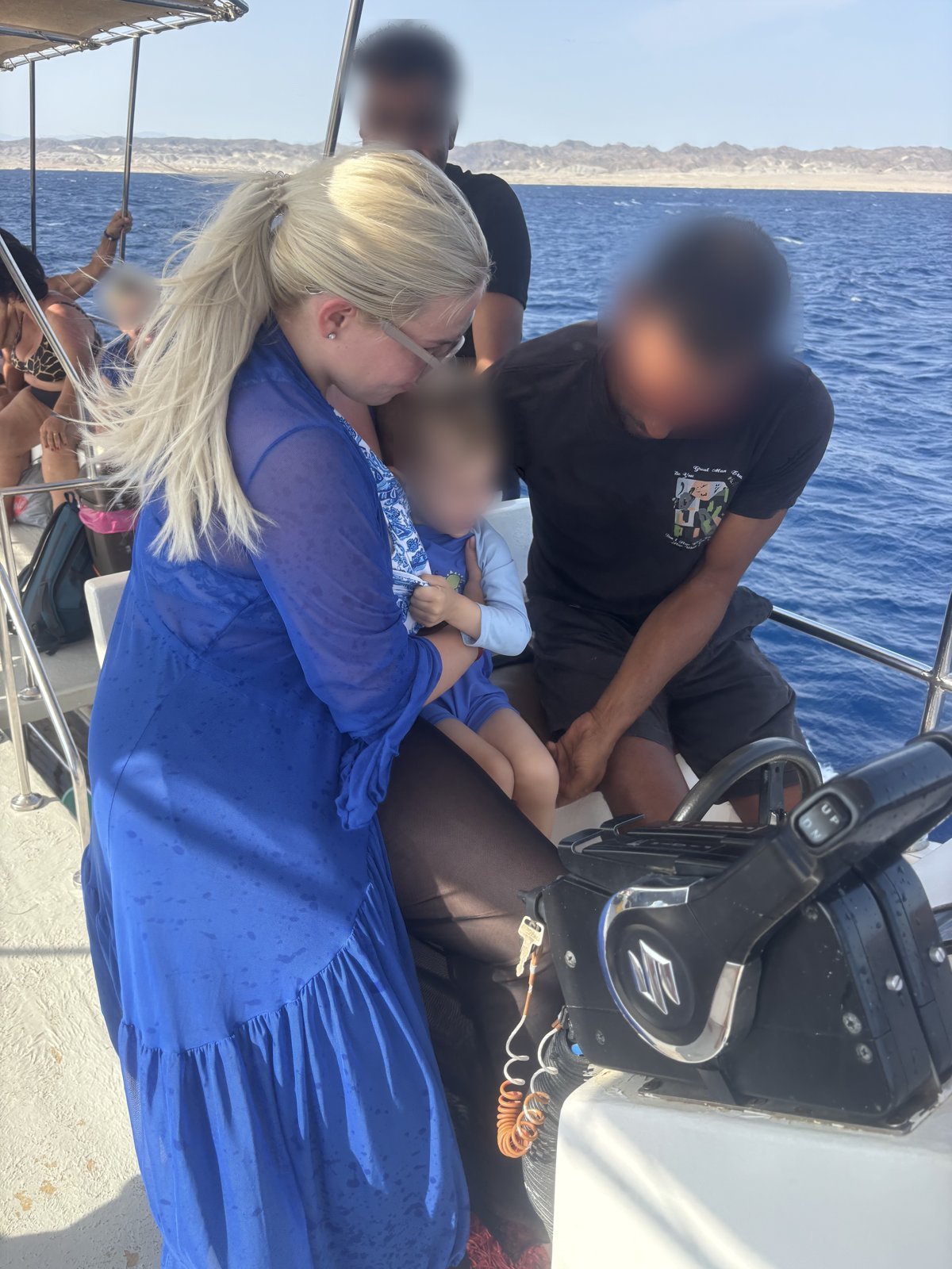 A woman holding a toddler at the helm of a day-trip boat on the open Red Sea